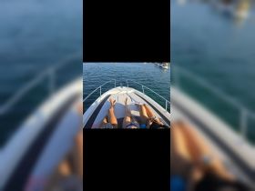 Three friends relax on the bow of a boat, enjoying the sun and water — a perfect moment for friendship and leisure on the water.