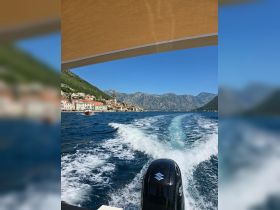 A scenic view from a boat cruising through clear waters, showcasing the stunning coastline and mountains — perfect for exploring beautiful destinations.