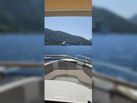 A scenic view from the bow of a boat, showcasing a large cruise ship docked against a mountainous backdrop — perfect for exploring coastal destinations.
