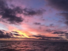 A stunning sunset over the ocean, showcasing vibrant colors in the sky, but the image lacks clarity.