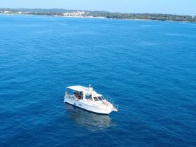 An aerial view of a boat cruising through clear blue waters, showcasing a perfect day on the water with guests enjoying the experience.