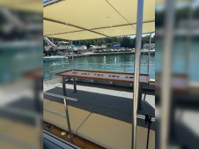 Interior view of a boat's seating area featuring a spacious table and comfortable cushions, perfect for relaxing or dining while enjoying the water.