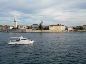 A scenic view of a boat cruising near a picturesque coastal town, showcasing the blend of water and architecture — perfect for sightseeing tours.