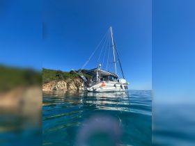 A stunning view of a sailboat anchored in calm waters, surrounded by lush greenery and clear blue skies — perfect for serene sailing adventures.