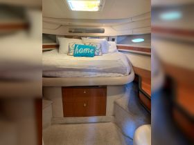 Cozy cabin interior featuring a comfortable bed adorned with decorative pillows, perfect for relaxing on a boat getaway.