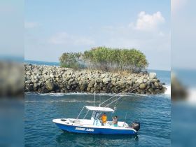 Two fishermen enjoy a day on the water aboard their boat, surrounded by scenic coastal views and rocky formations — a perfect setting for a fishing adventure.