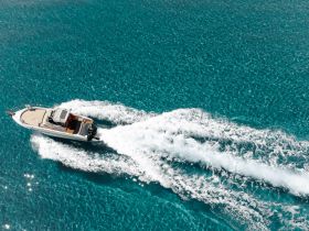 A stunning aerial view of a speedboat cruising through crystal-clear turquoise waters, showcasing the beauty of boating adventures.