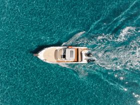 Aerial view of a sleek speedboat cruising through crystal-clear turquoise waters, perfect for exploring coastal destinations.
