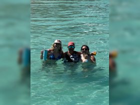 A fun group of friends enjoys refreshing cocktails while swimming in crystal-clear waters, perfect for a memorable day on the water.