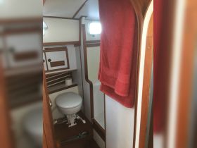 Interior view of a boat's bathroom, featuring a toilet and a towel, showcasing the cozy cabin space onboard.