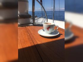 A serene moment aboard a boat featuring a cup of coffee on a polished wooden table, perfect for enjoying the tranquil sea views.