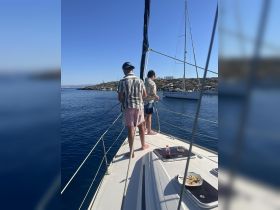 Two friends enjoy a day of fishing on a sailboat, surrounded by calm blue waters — a perfect way to experience the beauty of the sea.