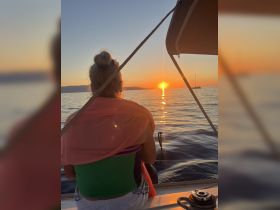A serene sunset view from a boat, featuring a guest enjoying the tranquil moment — perfect for romantic evenings or peaceful getaways on the water.