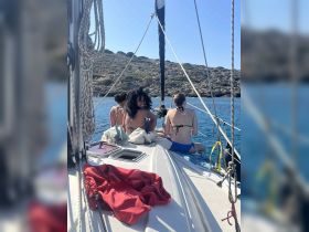 A group of friends enjoys a sunny day sailing, relaxing on the deck of a boat with stunning ocean views — perfect for summer adventures and memorable outings.