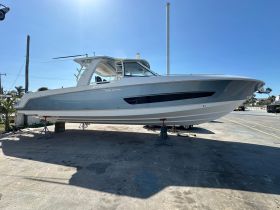A sleek 420 Outrage boat displayed on the dock, showcasing its modern design and structure under a clear blue sky.