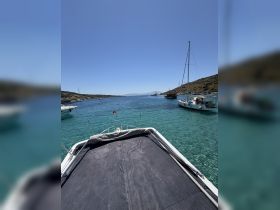 A stunning view of a boat anchored in crystal-clear waters, showcasing the serene surroundings and nearby vessels — perfect for a relaxing day on the water.
