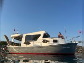 A man relaxes on the deck of the yacht 'Kaçamak' as the sun sets, showcasing a perfect moment of leisure on the water.