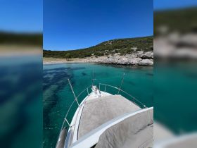 A stunning view from the front of a yacht, showcasing clear turquoise waters and a serene beach backdrop, perfect for a relaxing day on the water.