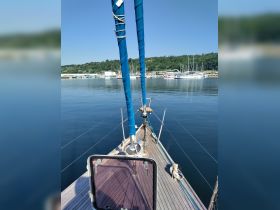 A serene view from the bow of a sailboat, showcasing the vessel's structure against a calm marina backdrop, perfect for sailing enthusiasts.