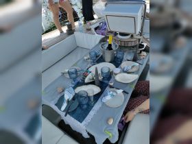 An elegantly set dining table on a boat, featuring cocktails and decorative elements, perfect for a luxurious onboard dining experience.
