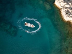 An aerial view captures a speedboat making thrilling turns in crystal-clear waters, showcasing the excitement of water sports and adventure on the open sea.