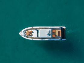 Aerial view of a couple sunbathing on a stylish boat in crystal-clear waters, perfect for a relaxing day on the water.