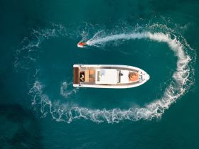 An aerial view captures a speedboat in action, with guests enjoying the thrill of the ride in vibrant turquoise waters — perfect for adventure seekers.