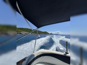 A dynamic view from the helm of a speedboat cruising through clear waters, showcasing the beautiful coastline and the boat's wake.