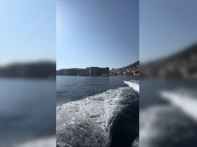 A scenic view of a historic coastline with a harbor, captured while cruising on the water, showcasing the beauty of the destination.