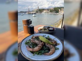 A beautifully plated dish of grilled shrimp served with fresh greens, perfect for enjoying a meal by the water while soaking in the scenic views.