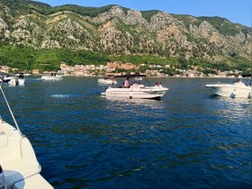 A lively scene of multiple boats navigating through sparkling waters, surrounded by stunning mountainous landscapes — perfect for a day of adventure on the water.
