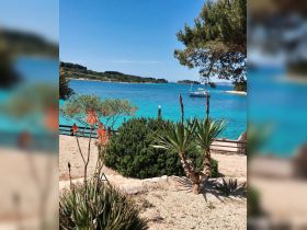 A stunning view of a turquoise coastline with a sailboat anchored in the distance, perfect for showcasing the beauty of island getaways and serene beach destinations.