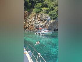 A young boy enjoys a relaxing swim in crystal-clear waters while a boat is anchored nearby, capturing the essence of summer fun and adventure.