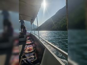 A serene moment on a boat with stunning mountain scenery and sunlight reflecting off the water, perfect for capturing the beauty of a day on the lake.