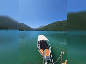 A scenic view of a boat docked in tranquil waters, surrounded by lush green mountains — an ideal setting for exploring nature.