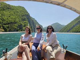 Three friends enjoy a sunny day on a boat surrounded by stunning mountain scenery, perfect for creating unforgettable memories on the water.