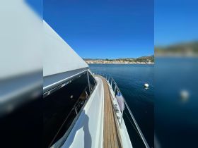 A stunning view of a yacht's side deck, showcasing the sleek design against a clear blue sky and calm waters, perfect for luxury cruising.