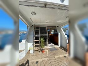 An inviting interior view of a yacht's cabin featuring a staircase, seating area, and a glimpse of the helm, perfect for relaxing while enjoying the scenic views.