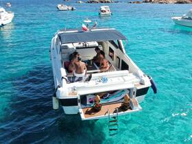 A lively group enjoys a sunny day on a boat, surrounded by crystal-clear turquoise waters — perfect for swimming and relaxation.