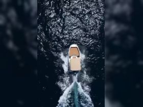 Aerial view of a sleek boat cruising through shimmering waters, showcasing its elegant design and smooth movement.