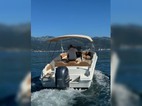 A speedboat navigates through calm waters with a captain at the helm, showcasing the thrill of boating adventures in a picturesque setting.