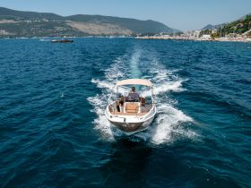 A boat speeds through the vibrant blue waters, showcasing a scenic coastal backdrop — perfect for adventure seekers and ocean enthusiasts.