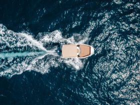 Aerial view of a sleek speedboat cruising through shimmering blue waters, showcasing the beauty of boating adventures.