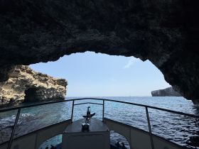 A stunning view from inside a boat looking out through a natural cave, showcasing the beautiful coastline and clear waters — perfect for adventure seekers exploring hidden gems.
