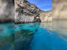 A stunning view of a natural cave along a rocky coastline, surrounded by crystal-clear turquoise waters — a perfect destination for boating adventures.