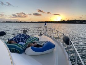 A serene sunset view as a family relaxes on the deck of a boat, showcasing a perfect moment of tranquility on the water.