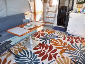 Cozy interior of a boat featuring a comfortable seating area and dining table, perfect for relaxing and enjoying meals while on the water.