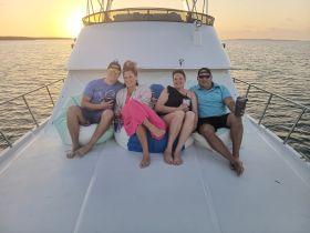 A group of friends relaxes on the deck of a boat at sunset, enjoying drinks and each other's company — a perfect setting for memorable gatherings on the water.