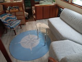 Cozy interior of a boat featuring a comfortable seating area and a stylish compass rug, perfect for relaxing while at sea.