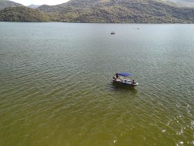 A small boat with passengers enjoys a scenic day on the water, surrounded by lush hills — perfect for leisurely outings and nature exploration.